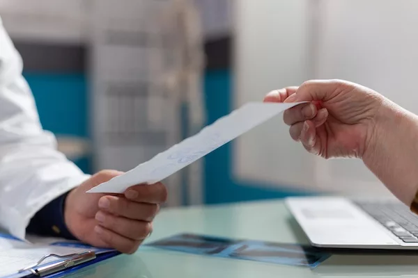 Physician giving prescription document to patient in cabinet